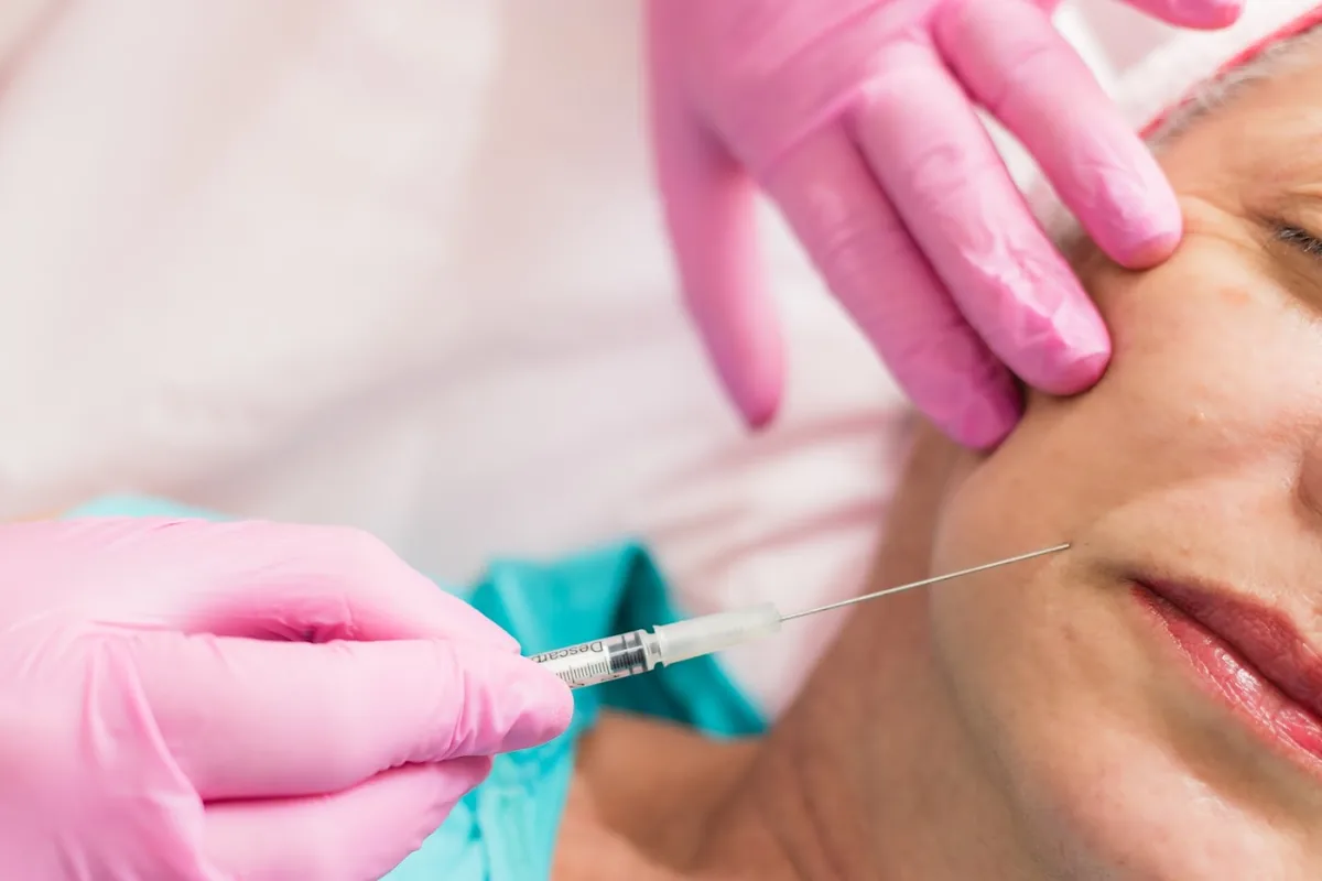 Dra. Audrey realizando aplicação facial com luvas, em ambiente clínico